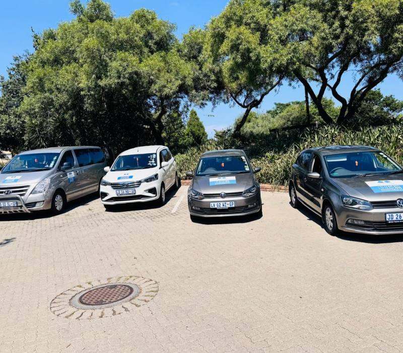 Well-maintained school transport vehicles parked under trees in Fourways